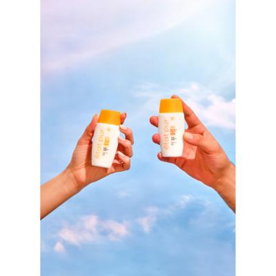 Sunscreen Etat Pur Mineral Fluid SPF 50+ bottles with orange caps held against a blue sky on Tampa Home & Garden Store