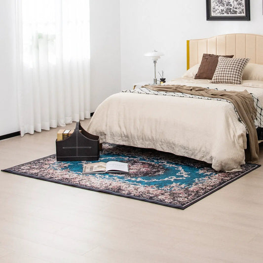 Area rug with blue teal borders and floral pattern under beige bed in bright bedroom on Tampa Home & Garden Store