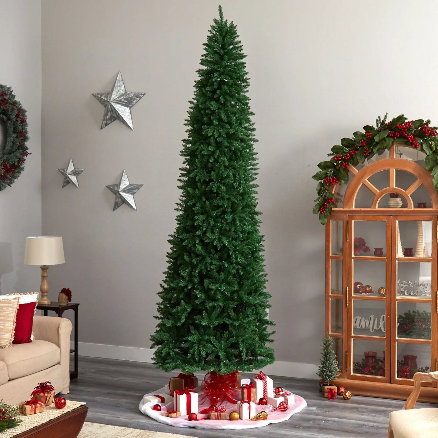 Slim green Mountain Pine Christmas Tree indoors with wrapped gift boxes at its base on Tampa Home & Garden Store