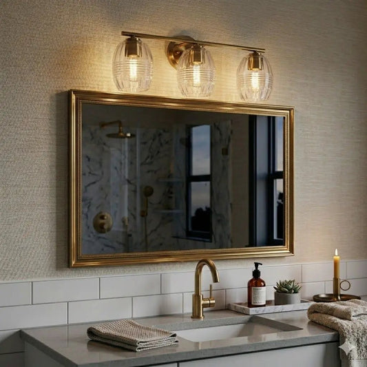 Luster 3-light vanity wall lamp satin gold with clear glass shades above a bathroom mirror on Tampa Home & Garden Store