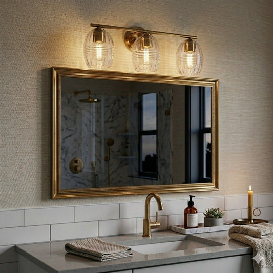 Luster 3-light satin brass vanity wall sconce with clear glass shades above bathroom sink on Tampa Home & Garden Store