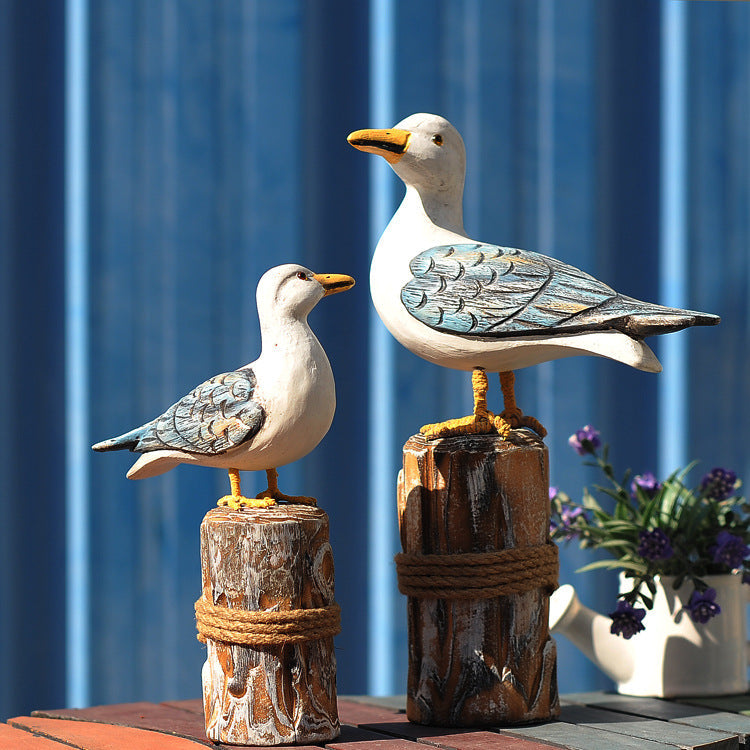 Two handcrafted white and blue-painted wooden seagull statues perched on rope-wrapped posts on Tampa Home & Garden Store