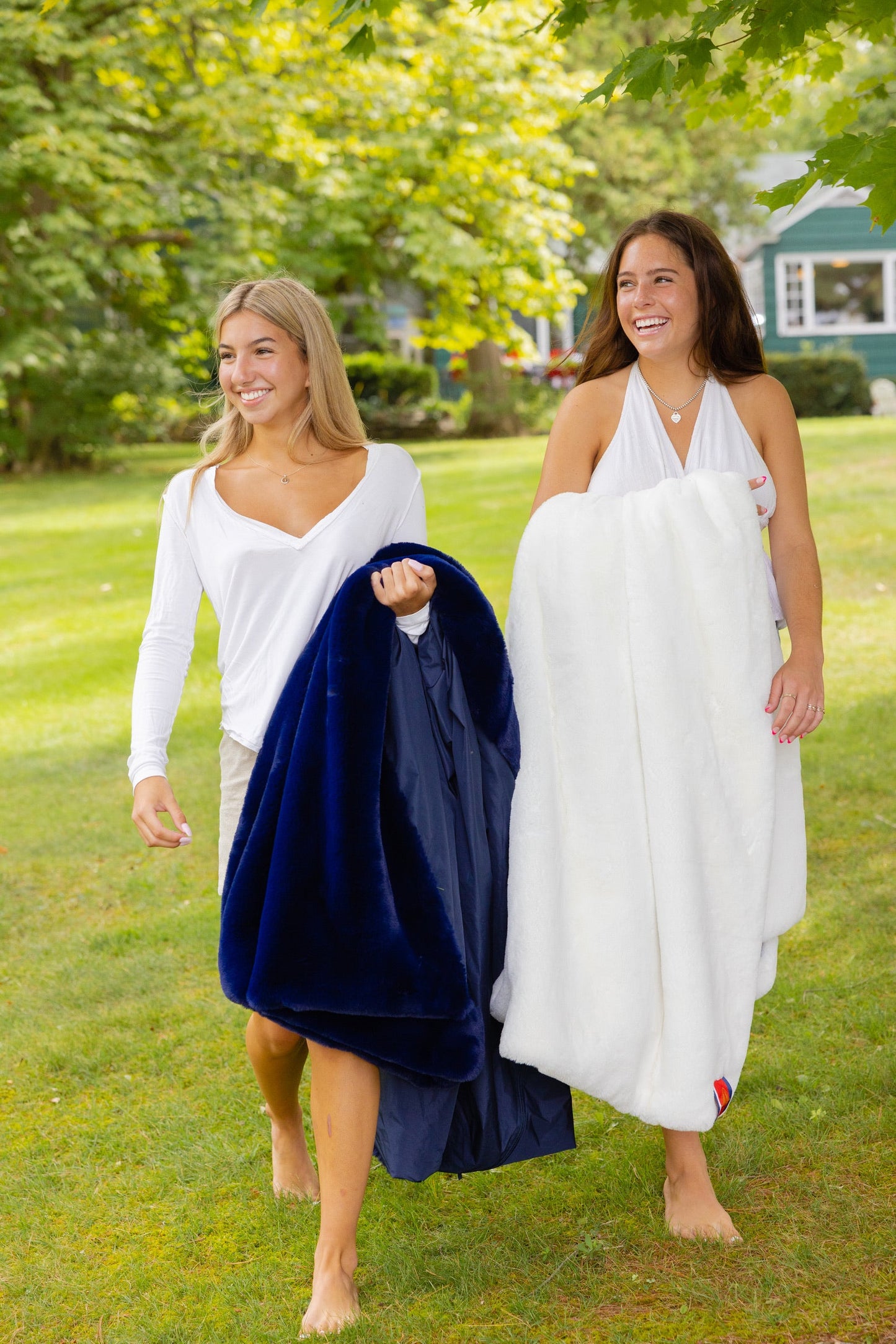 Villanova Large White Outdoor Blanket carried by two women outdoors on a lawn; navy blanket on Tampa Home & Garden Store