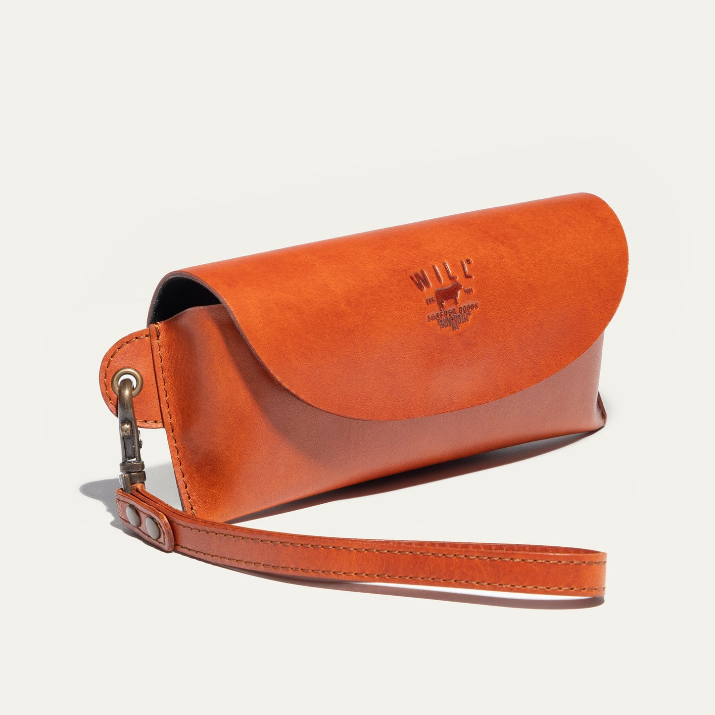 Eyeglass case by Will Leather Goods in orange leather with embossed logo on flap and strap on Tampa Home & Garden Store