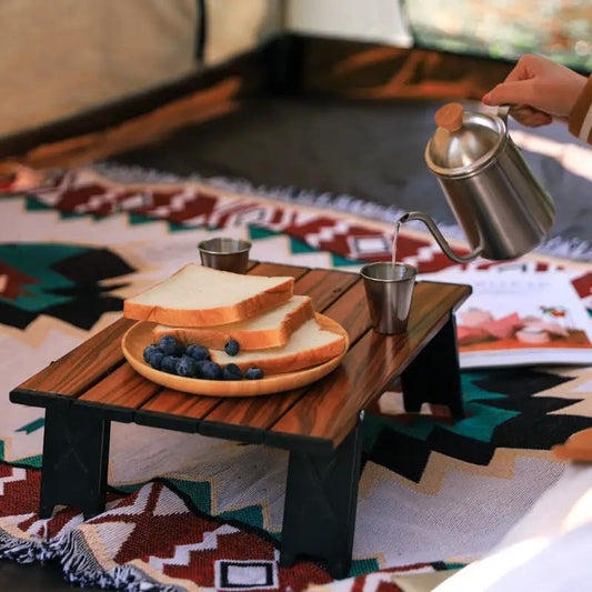Black portable aluminum folding picnic table with a wood-grain top on a camping blanket on Tampa Home & Garden Store