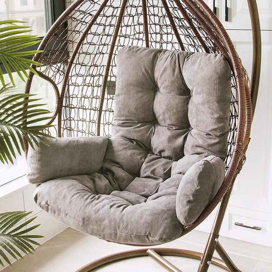 Hanging wicker egg chair with plush gray cushions and metal stand indoors, near a plant on Tampa Home & Garden Store