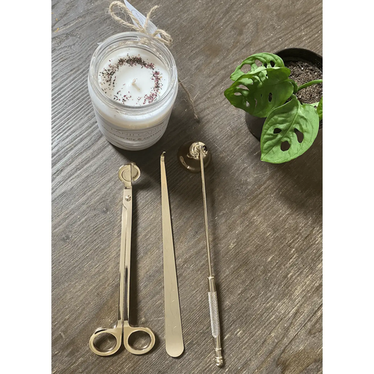 3 Piece Candle Care Kit with gold-tone tools beside White Cliff candle with petals on wood on Tampa Home & Garden Store