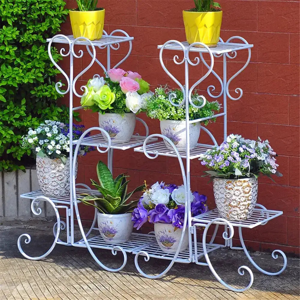 Ornate white 4-tier metal plant stand with curled scrollwork and potted plants on Tampa Home & Garden Store