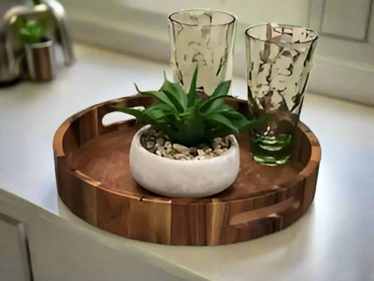 Round Acacia Wood Charcuterie and Serving Tray by Kalmar Home with plant and two glass holders on Tampa Home & Garden Store