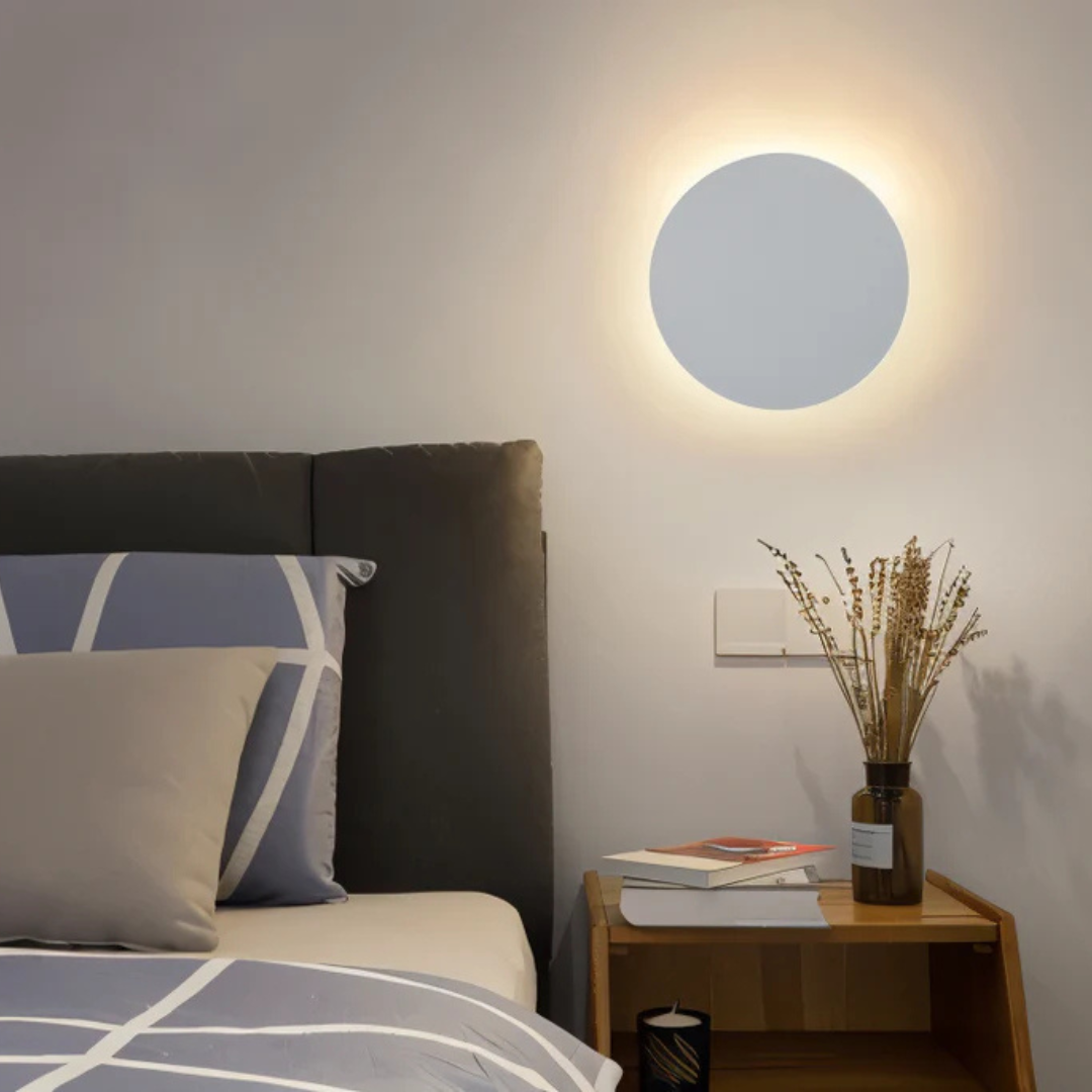 Modern LED Wall Lamp Moktan Sabai, circular white wall light with warm halo above bed near wooden nightstand on Tampa Home & Garden Store