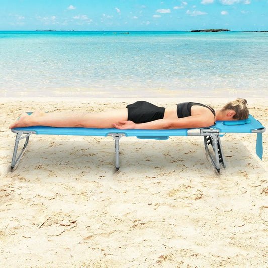 Folding turquoise beach lounge chair with pillow sunlounger on sandy beach with a person on Tampa Home & Garden Store