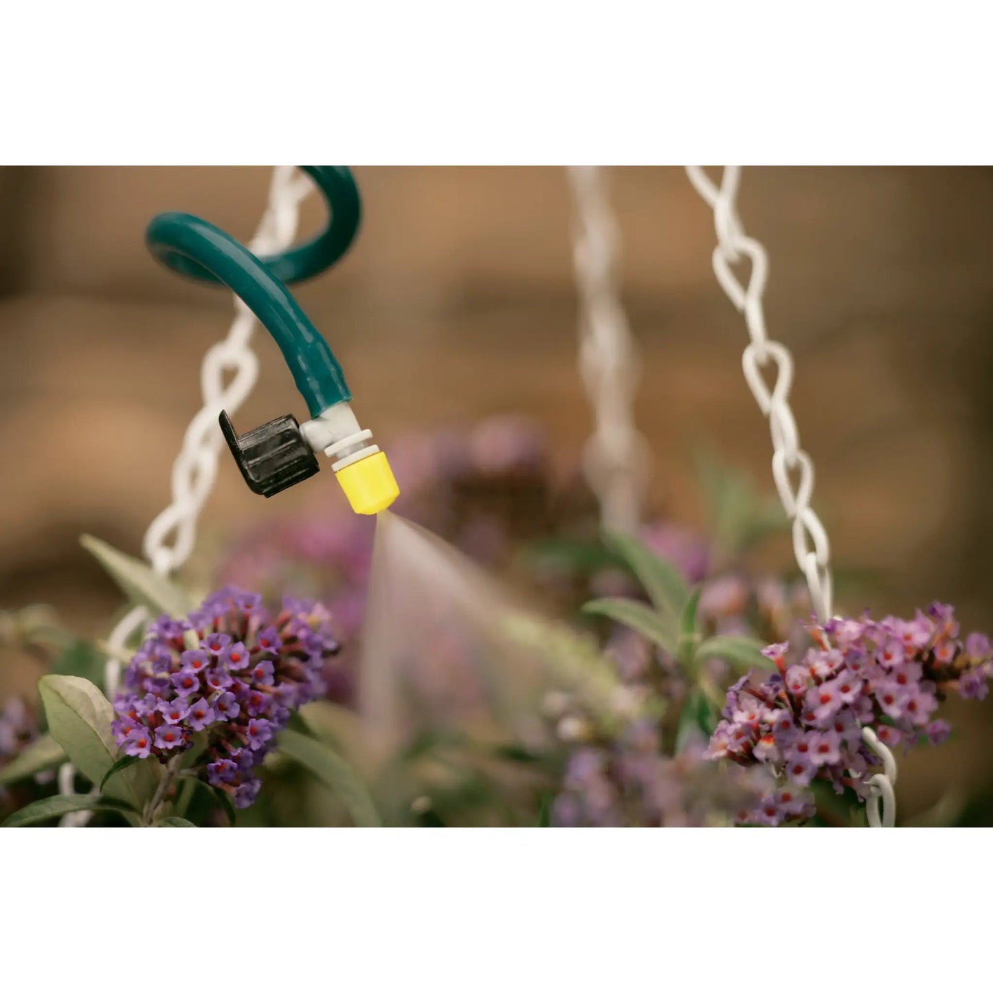 Quarter inch barb flex mist sprayer Orbit Irrigation on green hose amid white lights on Tampa Home & Garden Store