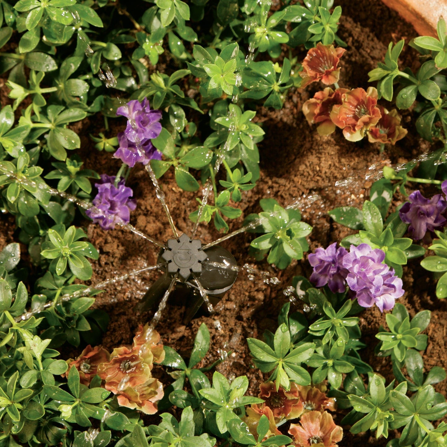 Quarter Inch Barb Multi-Stream Emitter on Stake by Orbit Irrigation in a garden with green foliage and purple blooms on Tampa Home & Garden Store