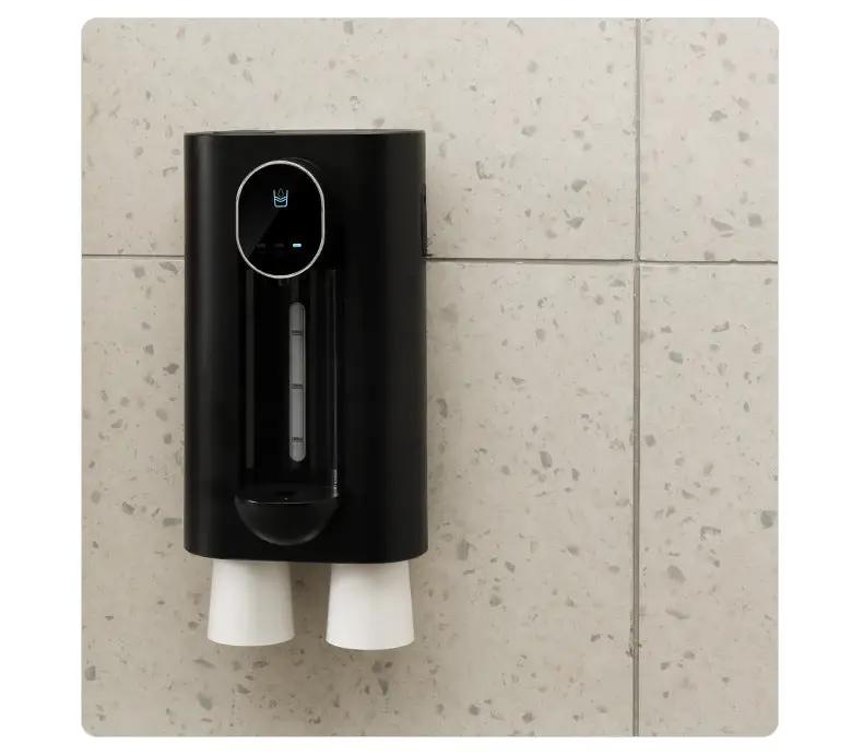 Black wall-mounted mouthwash dispenser with a visible level window and two white cups on Tampa Home & Garden Store