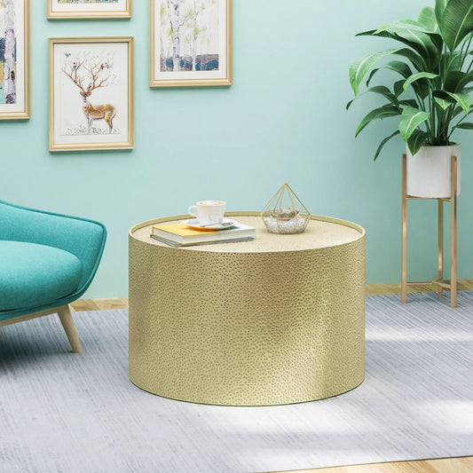 Gold iron coffee table with a perforated base and round beige top in a modern living space on Tampa Home & Garden Store