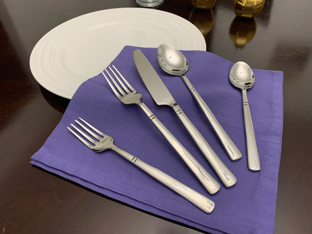 Vibhsa 20-piece stainless steel flatware set with forks spoons knives on purple napkin beside plate on Tampa Home & Garden Store