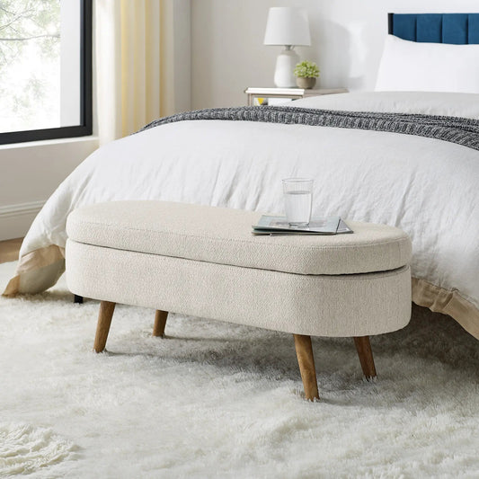 Ottoman Oval Storage Bench in beige linen with wooden legs in a cozy bedroom on Tampa Home & Garden Store