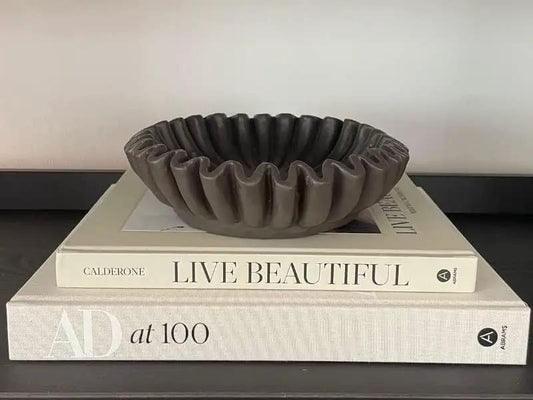 Groove Lotus Leaf Edge Decorative Bowl, gray ceramic with a ruffled rim, atop art books on Tampa Home & Garden Store