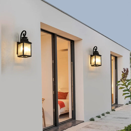 Two large outdoor wall lamps with glass and black metal frames beside doors on white exterior on Tampa Home & Garden Store