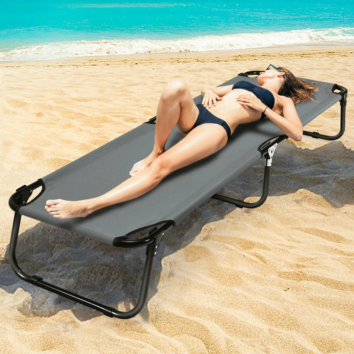 GemGear folding camping cot on beach; gray fabric with black frame, person lounging in swimsuit on Tampa Home & Garden Store