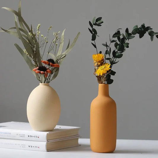 Ceramic vase set: two vases in beige and mustard with dried floral stems on a book stack on Tampa Home & Garden Store