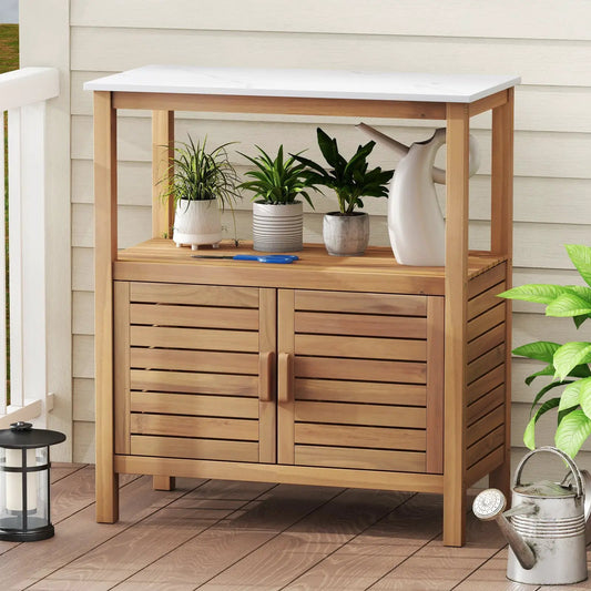 Outdoor potting bench in acacia wood with white top and slatted cabinet doors with three plants on Tampa Home & Garden Store