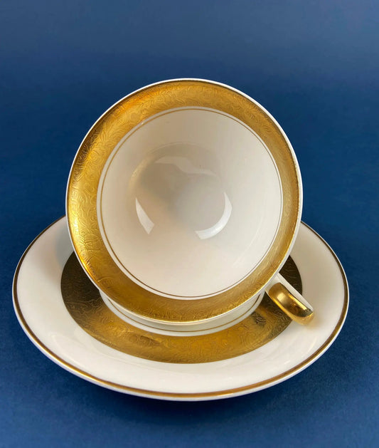 Teacup and saucer set in porcelain with gold band by Royal Jackson gold-rimmed plates stacked on Tampa Home & Garden Store