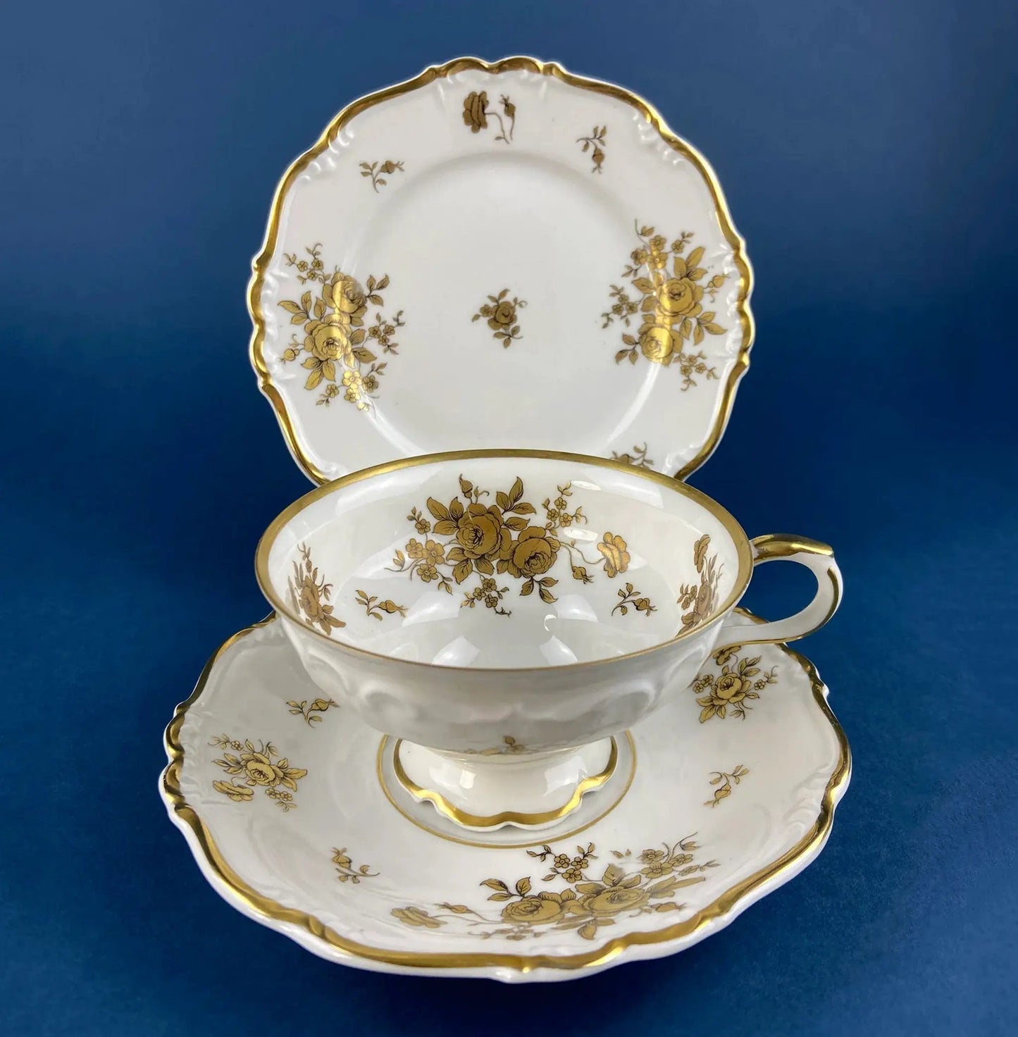 Teacups and saucers in white porcelain with gold scalloped rims and floral motifs, stacked on Tampa Home & Garden Store