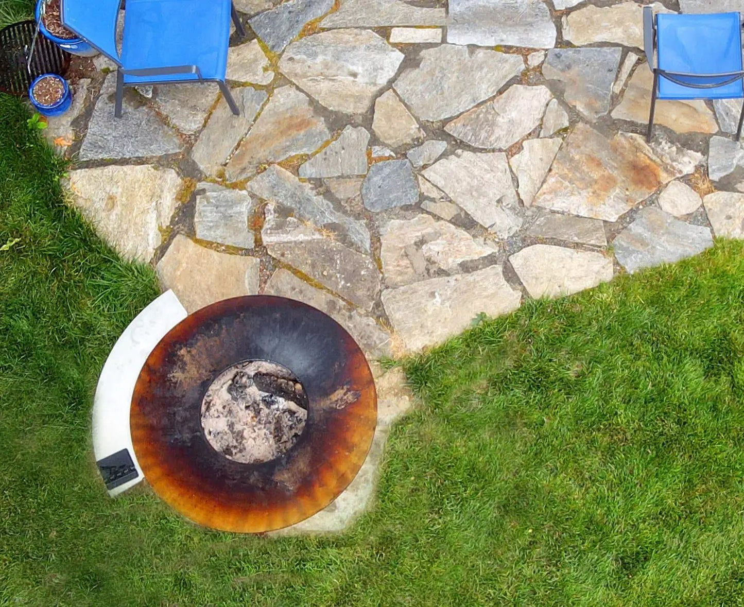 Arteflame Side Warming Table on Cooktop fire pit with rusted bowl on patio beside blue chairs on Tampa Home & Garden Store