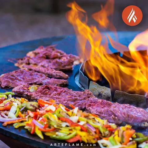Arteflame Stainless Steel Food Saver on grill with beef and colorful vegetables amid flames on Tampa Home & Garden Store