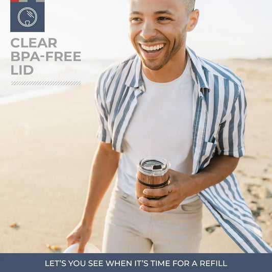 TRAPSKI Barrel 12oz Tumbler with wood barrel finish and clear BPA-free lid held on a sunny beach on Tampa Home & Garden Store