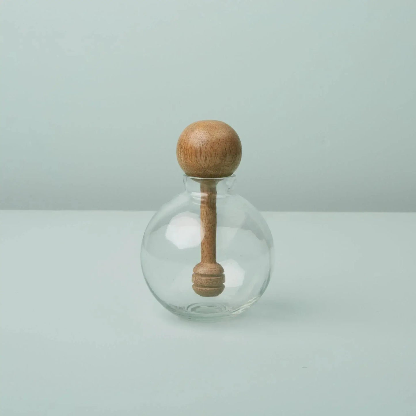 Decorative glass jar with round wooden stopper and carved spindle neck pale blue backdrop on Tampa Home & Garden Store