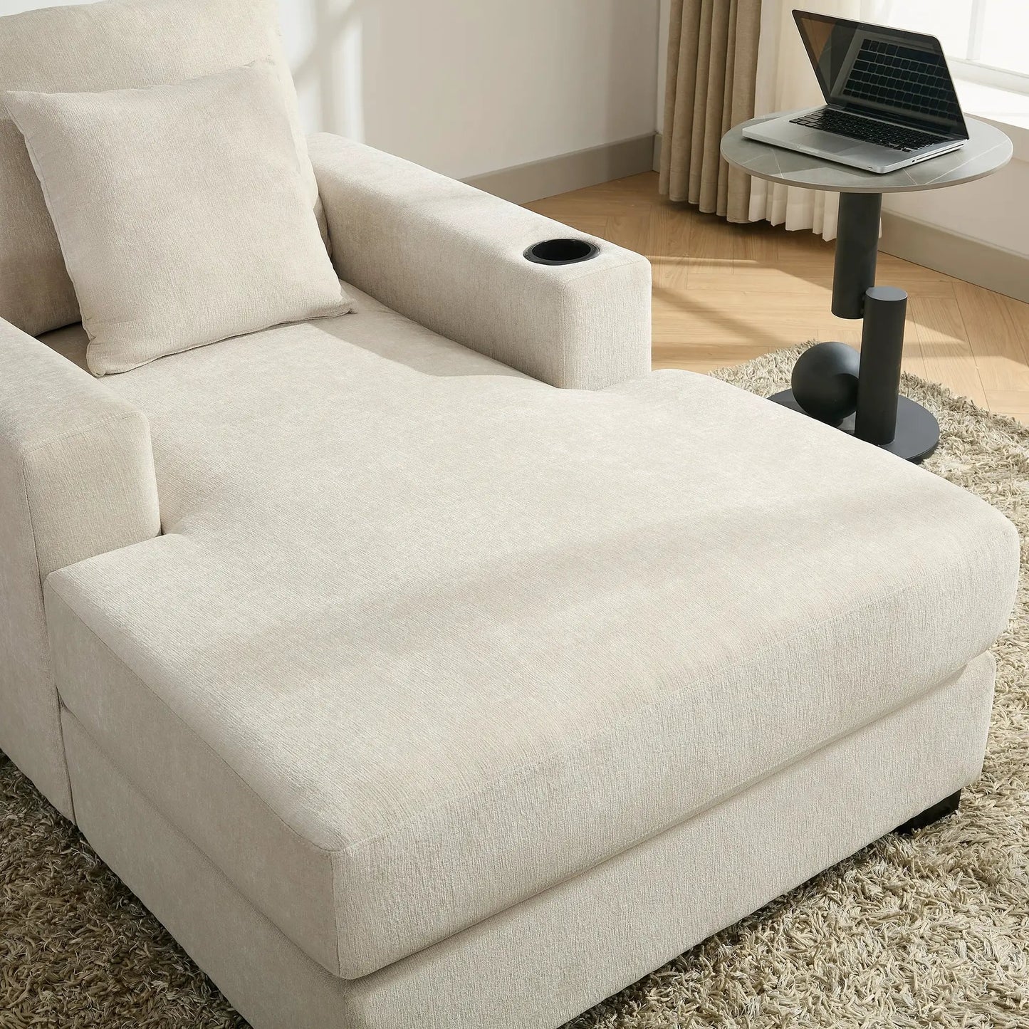Oversized beige chaise lounger with pillows and cup holder beside a round table with laptop on Tampa Home & Garden Store
