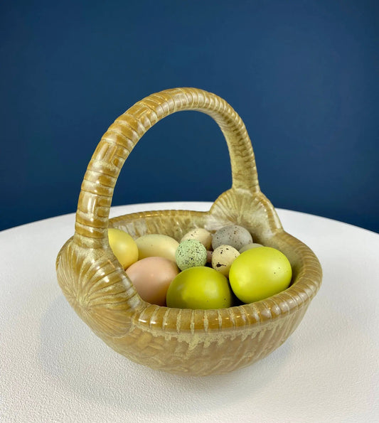 Ceramic egg basket in gold-brown with woven handle holding pastel Easter eggs on Tampa Home & Garden Store