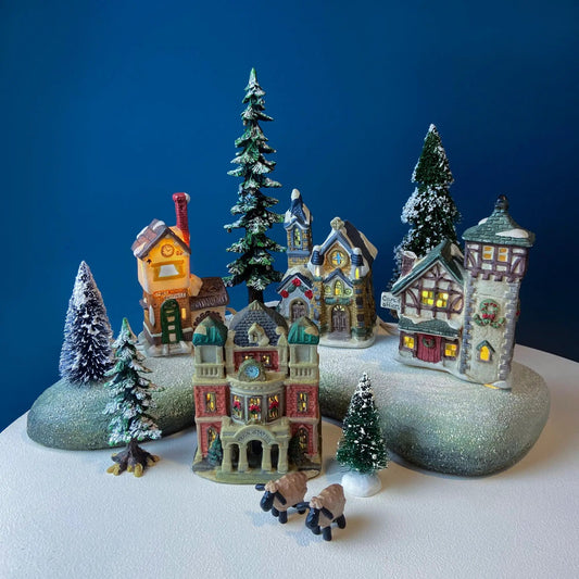 Illuminated Christmas village with snow-topped houses and trees on Tampa Home & Garden Store