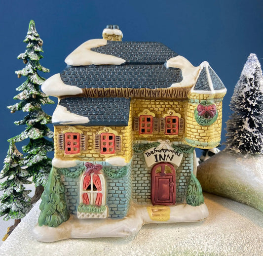 Porcelain Christmas Village Inn, illuminated with snow roof and red windows among trees on Tampa Home & Garden Store