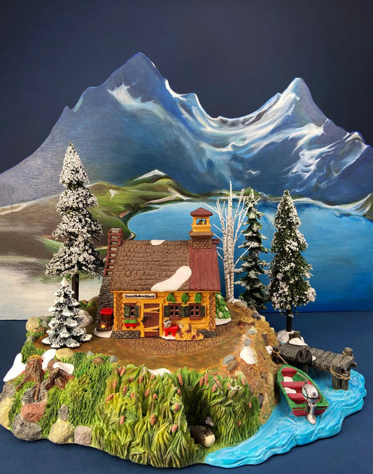 Christmas Village Platform and Pines: snow-dusted pines, rustic cabin, and mountain backdrop on Tampa Home & Garden Store