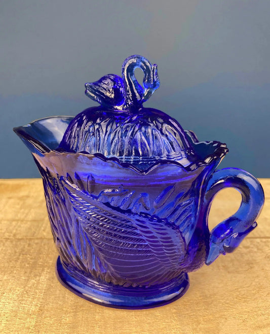 Cobalt blue glass creamer with swan-shaped lid finial and embossed reed pattern on Tampa Home & Garden Store