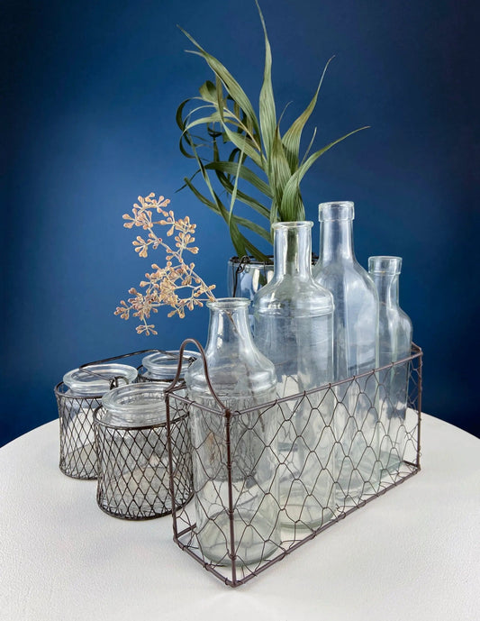 Rustic glass jars and bottles in a wire basket; clear glass decor on Tampa Home & Garden Store