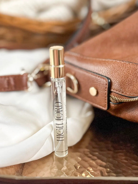 High Lord Travel Perfume vial with gold cap beside a brown leather bag on Tampa Home & Garden Store