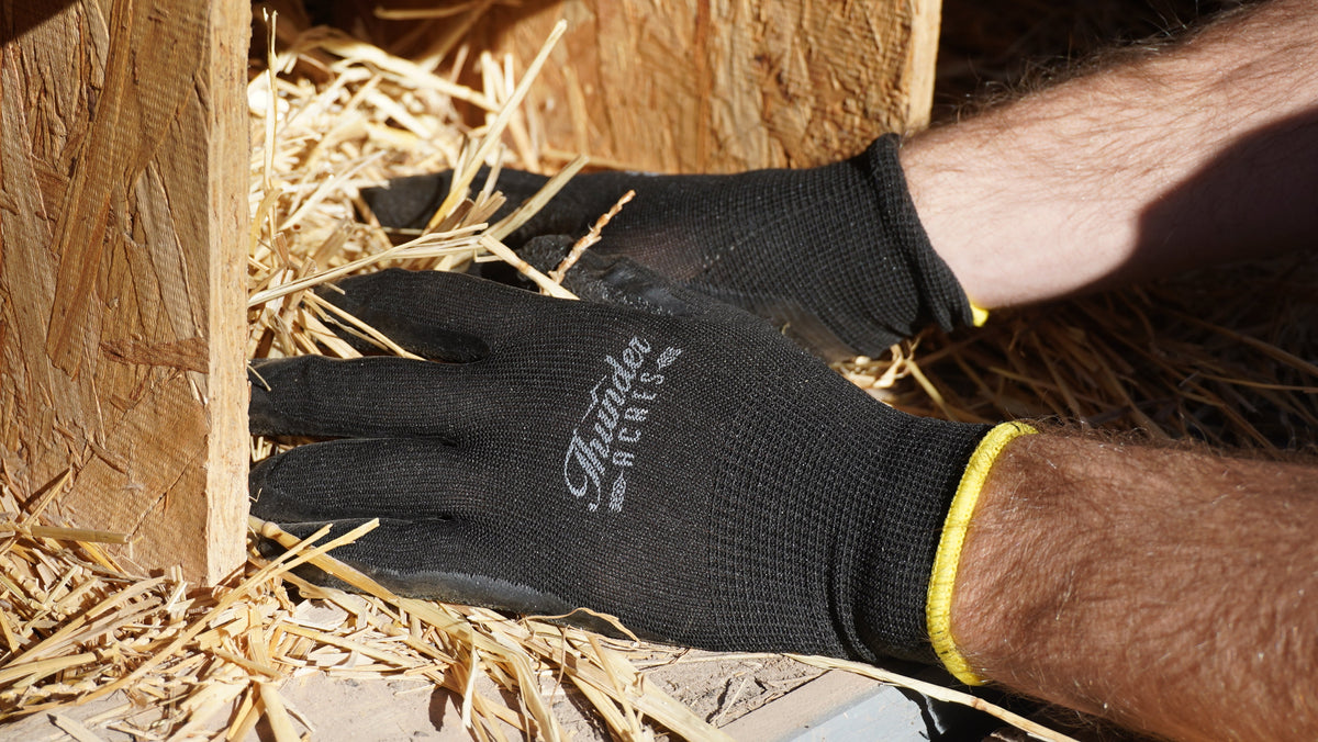 Garden gloves by Thunder Acres, black knit with yellow cuffs on straw mulch on Tampa Home & Garden Store