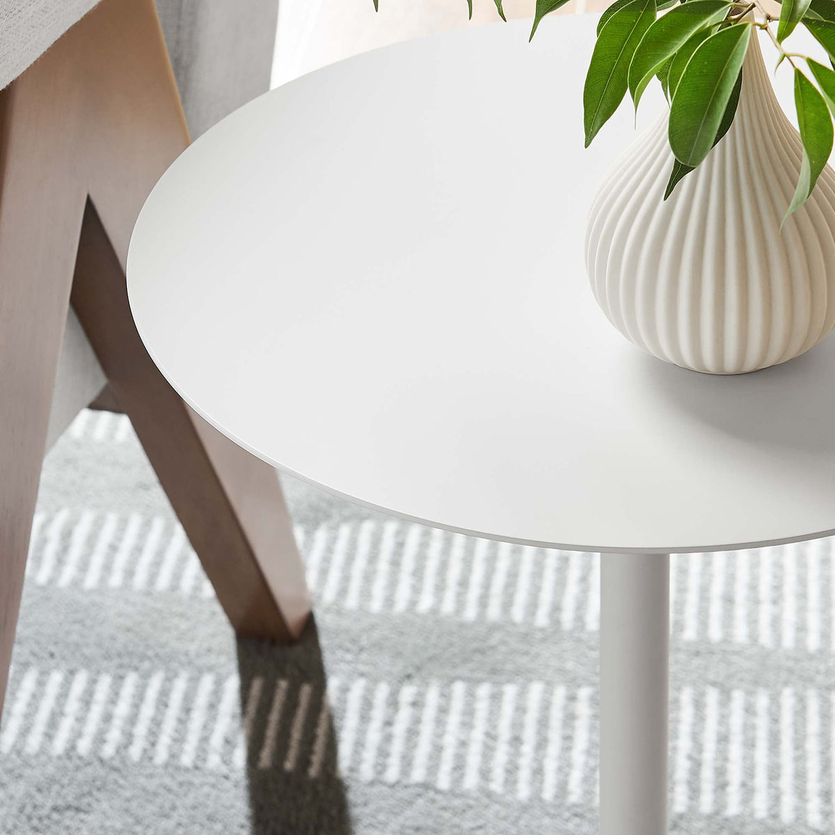 Aliza round white marble side table with wood legs and a ribbed white vase with green leaves on Tampa Home & Garden Store