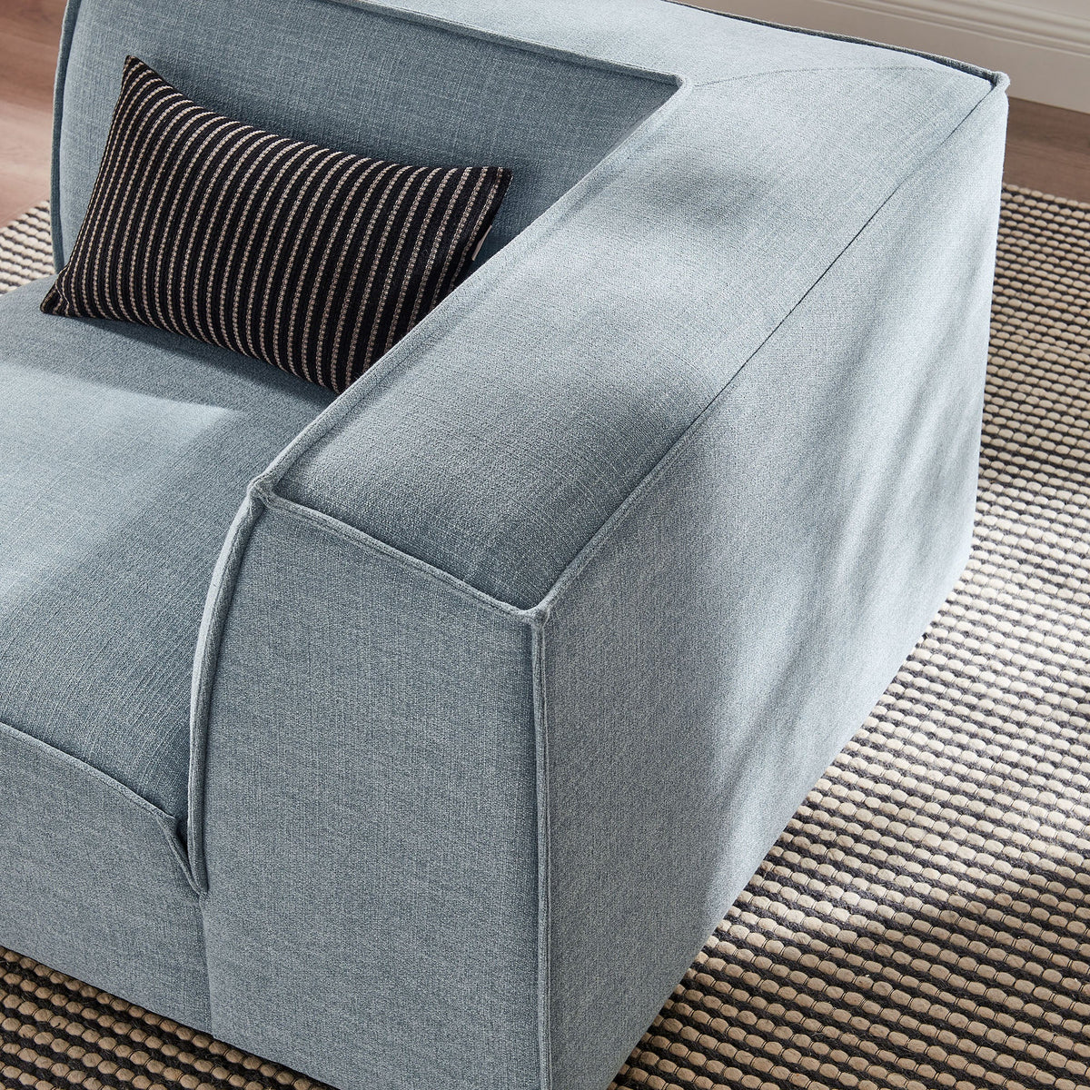 Modular corner chair in blue performance fabric with a black striped bolster pillow on Tampa Home & Garden Store