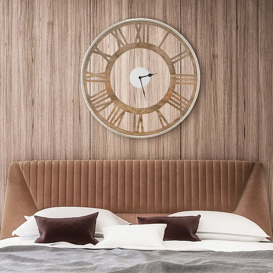 Round wooden wall clock with Roman numerals and black hands above a brown tufted headboard on Tampa Home & Garden Store