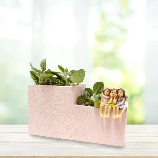 Pink stepped planter with green plants and four fairy figurines perched on lawn ornament on Tampa Home & Garden Store