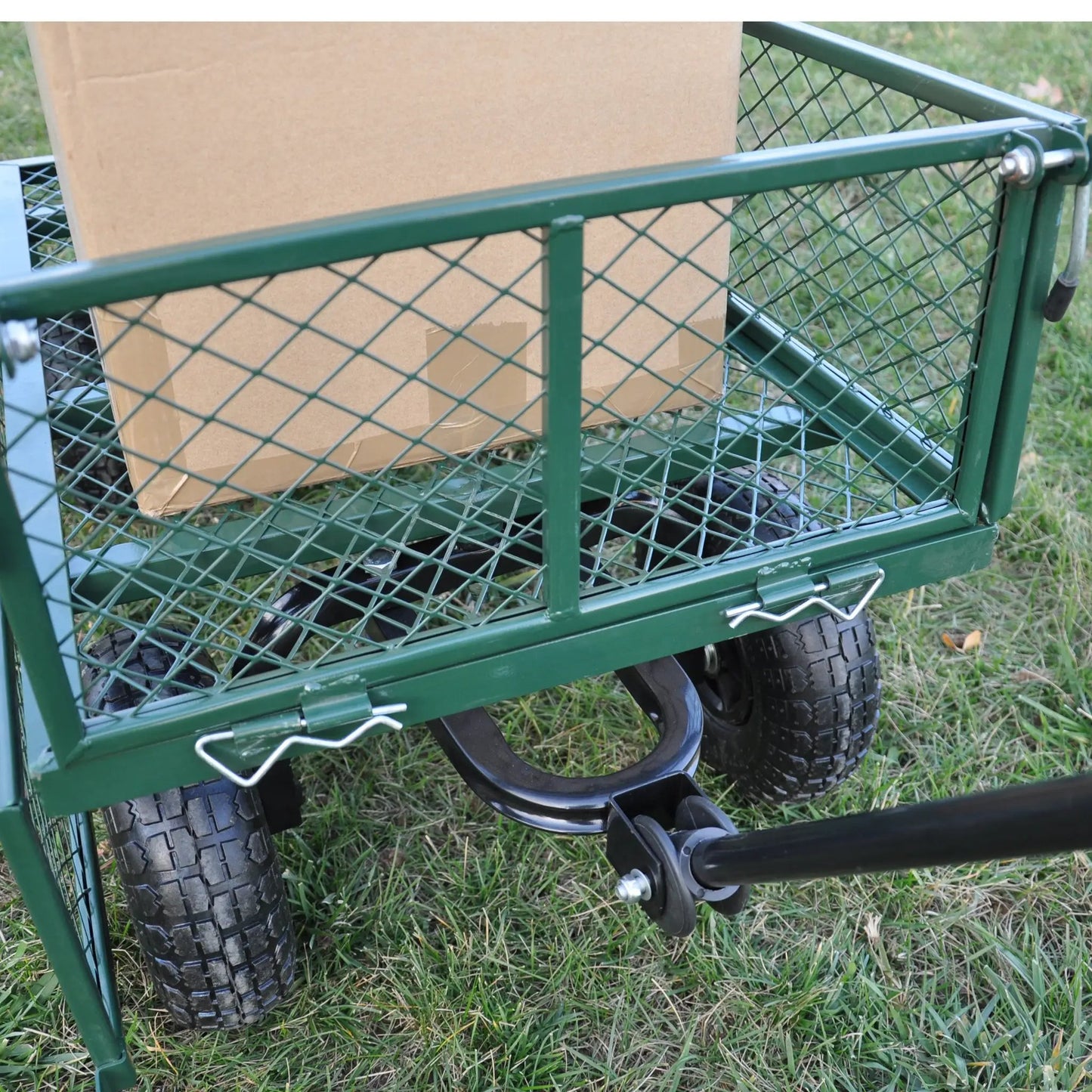 Green wagon cart with diamond mesh sides and dual tires carrying a cardboard box on Tampa Home & Garden Store