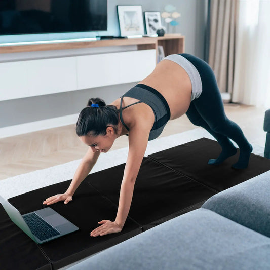 Folding gymnastics mat with carry handles in black, used for home workouts beside a laptop on Tampa Home & Garden Store
