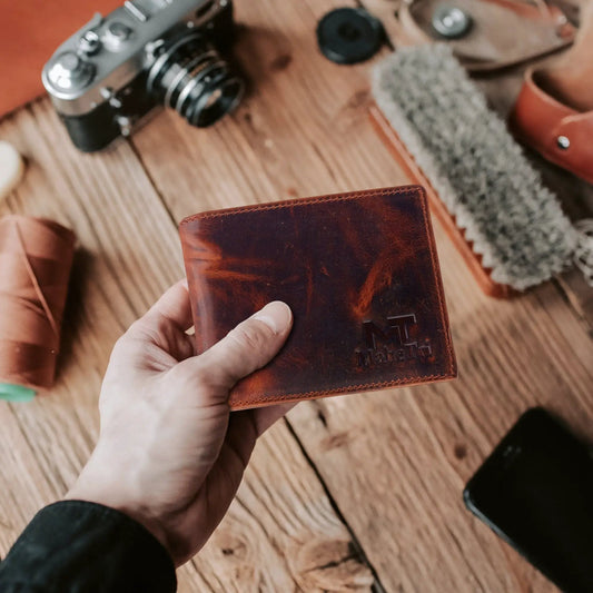 Forster bi-fold buffalo leather wallet in warm brown held in hand on wooden table on Tampa Home & Garden Store