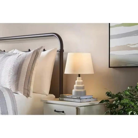 Small grey HomePacific desk lamp with a stacked base and white fabric shade on bedside nightstand on Tampa Home & Garden Store