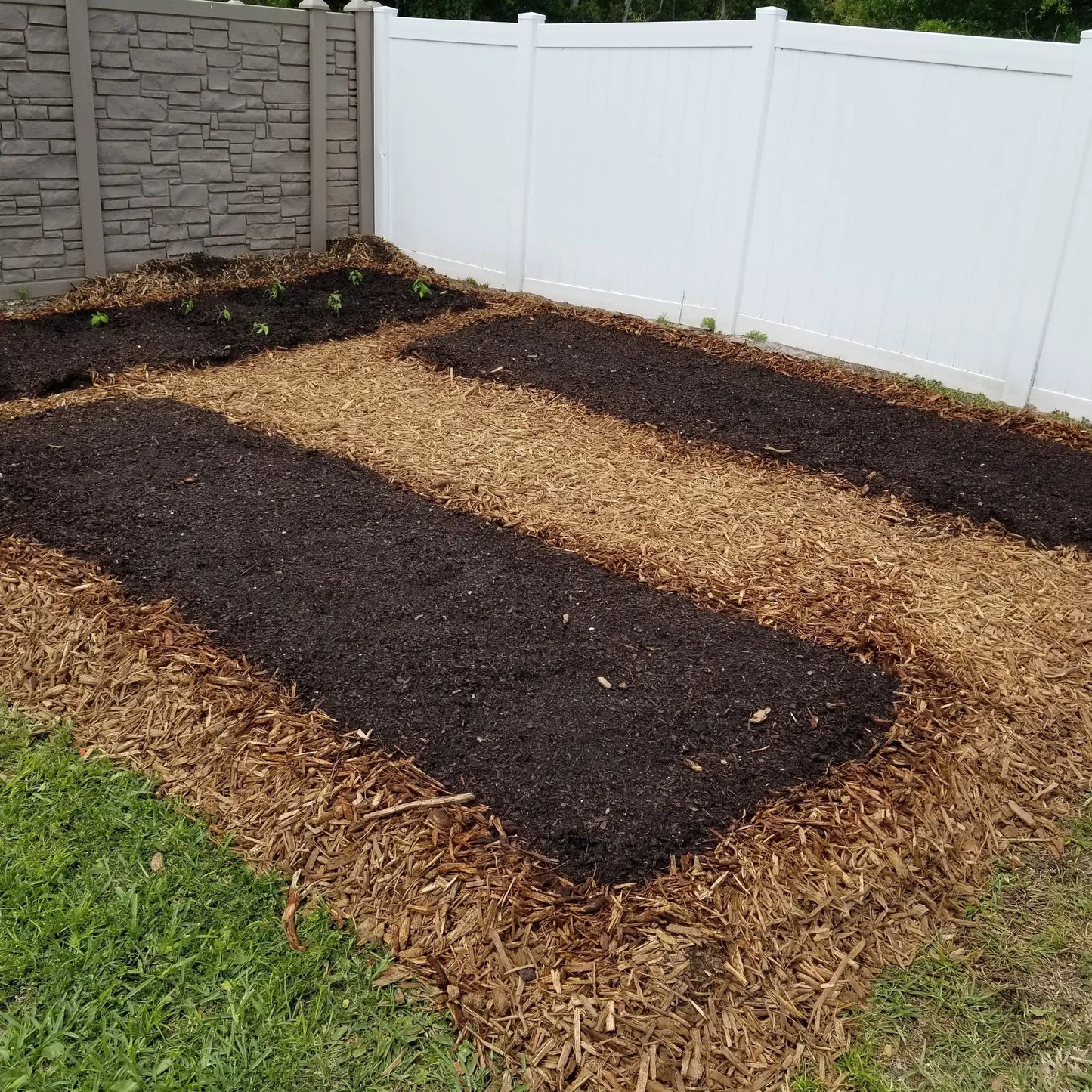 Garden Paper Roll Biodegradable weed barrier over mulched beds beside stone wall and fence on Tampa Home & Garden Store